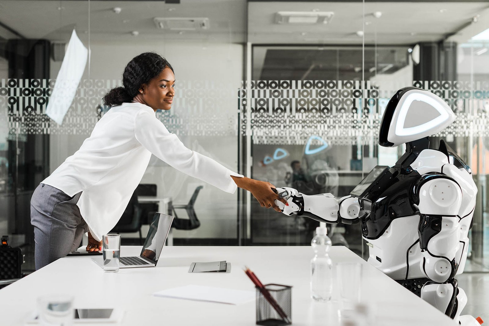 smiling african american businesswoman shaking hands with robot